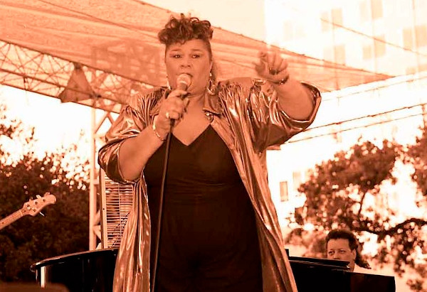 Etta James, cantora norte-americana de blues segurando um microfone durante apresentação.